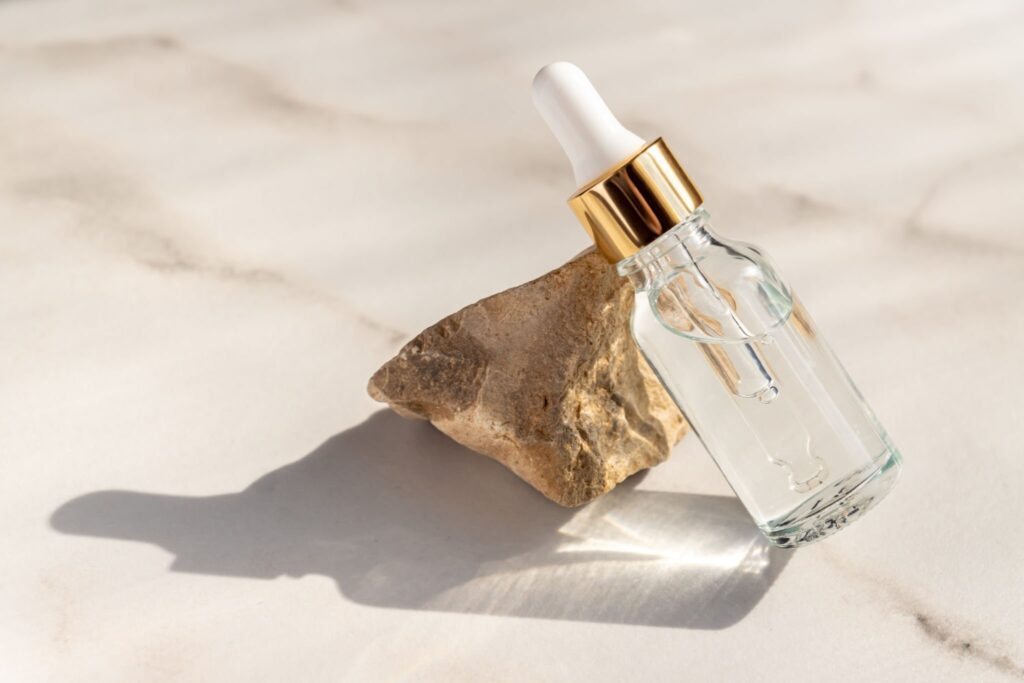 Serum, essential oils or fluid collagen in transparent glass bottle with pipette with snone on marble background. Natural Organic Spa Cosmetic Beauty concept