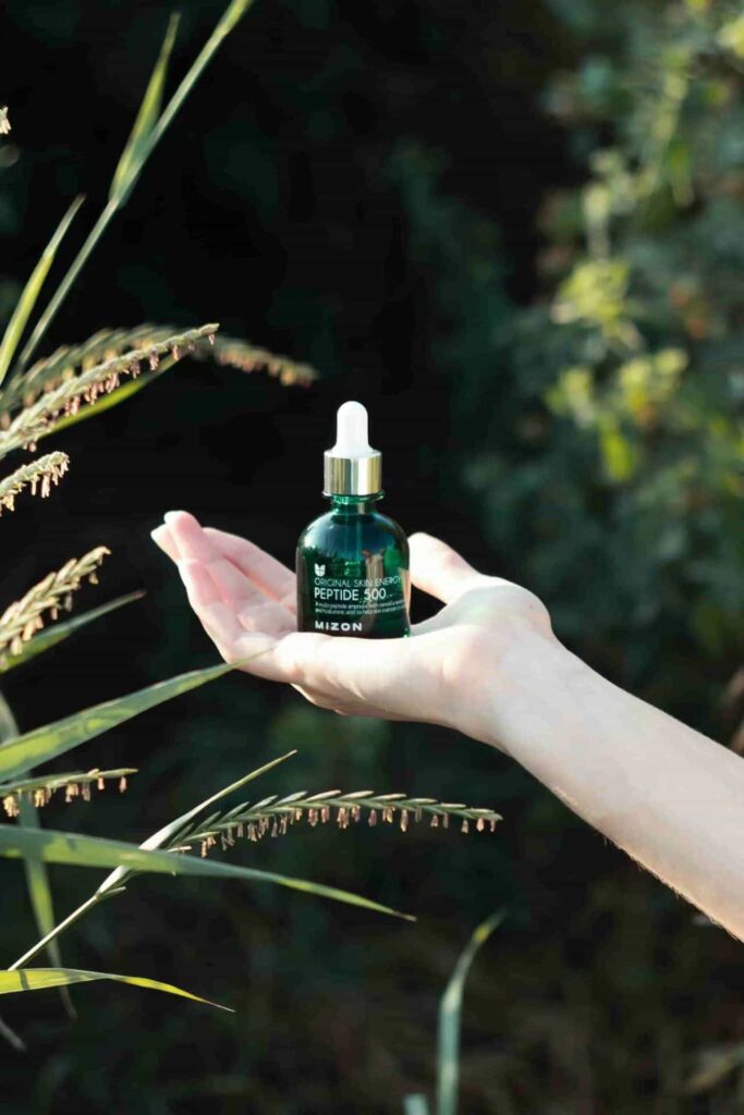 a hand holding a green glass essential oil bottle