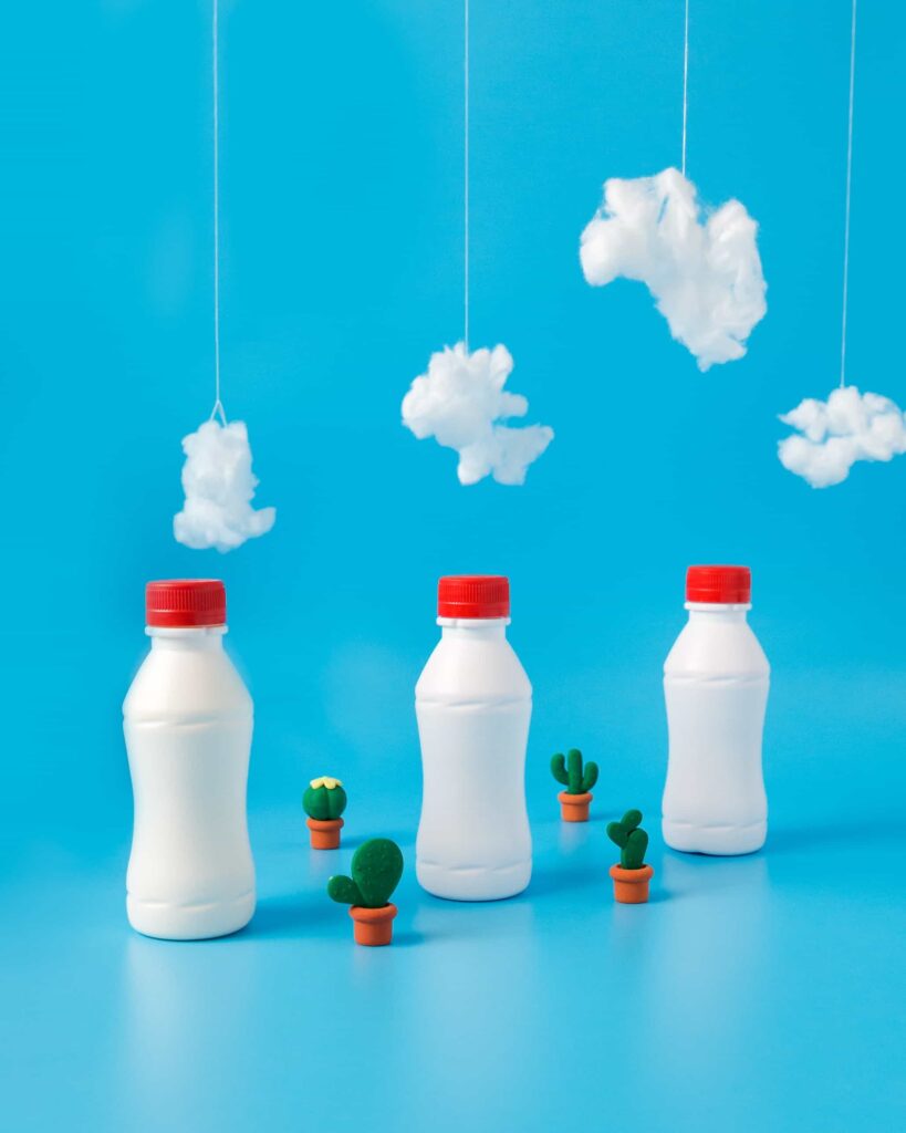 three plastic milk bottles with red plastic lids