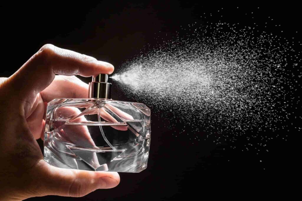spraying perfume on dark background, closeup