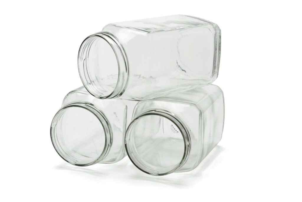 Three open glass jars stacked on white background