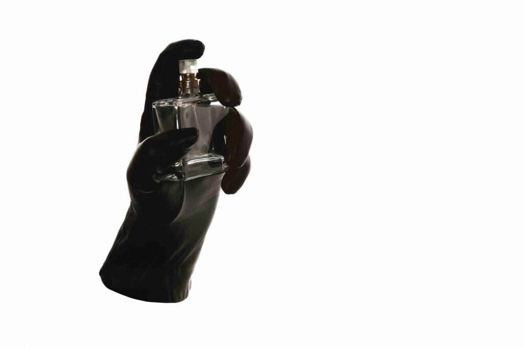 Black glove in hand shape holding a perfume bottle