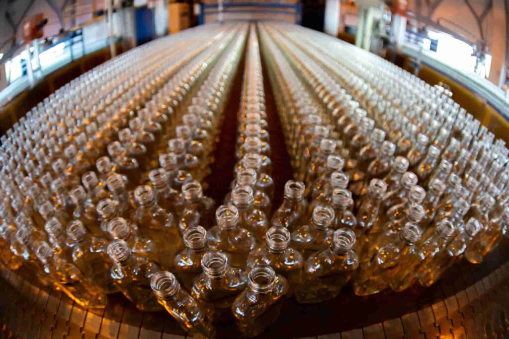 Many glass bottles on a factory conveyor.