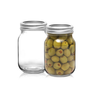 two glass mason jars with metal lids, one is empty, another is filled with green oliver